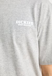 Gray cotton t-shirt featuring the text "DICKIES DEEP ROOTED" in white on the upper back. Soft texture, classic short-sleeve design.