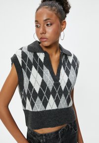 Zwart-witte argyle gebreide mouwloze sweater met een kraag, cropped ontwerp en een gestructureerde ribbelsrand.