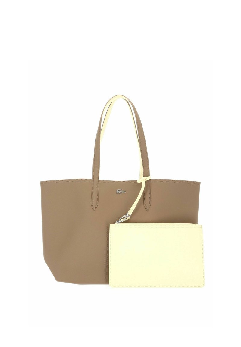 Borsa tote in pelle marrone con due manici e una piccola pochette crema con zip staccabile attaccata a un manico.