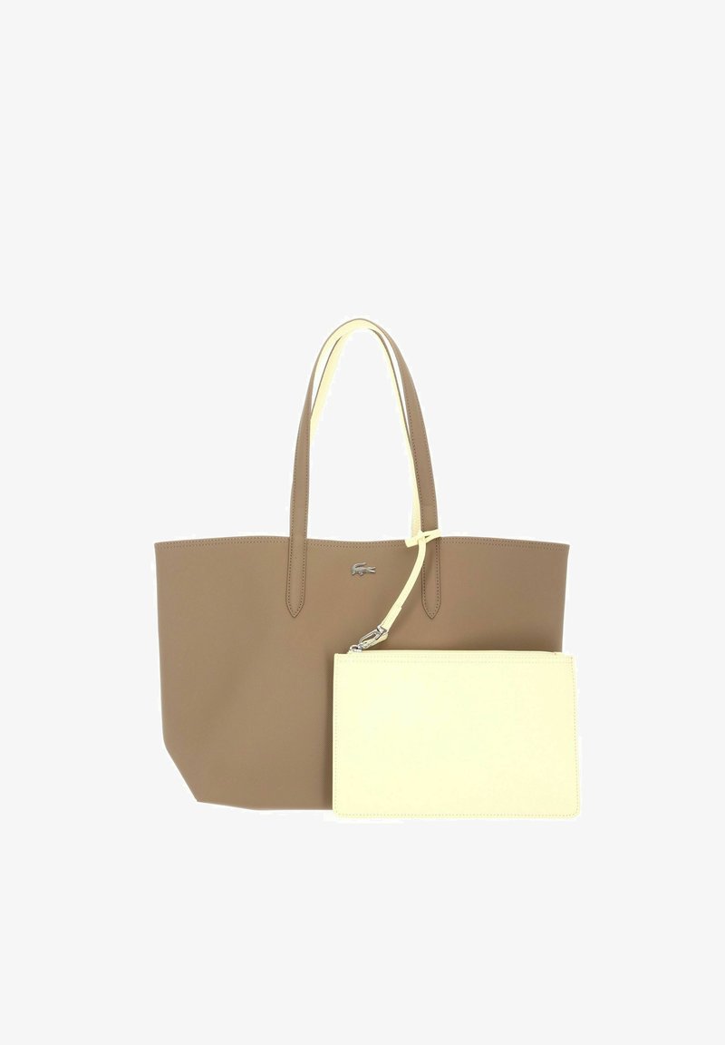 Borsa tote in pelle marrone con due manici e una piccola pochette crema con zip staccabile attaccata a un manico.