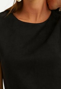 Haut noir à manches courtes avec une texture lisse, un col rond et un léger éclat. Pas de motifs ni de embellissements. Design simple.