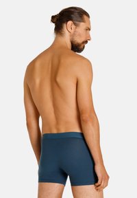 Heren boxershorts in een donkere teal kleur. Gemaakt van een gladde stof met een zachte tailleband. Van achteren weergegeven, met een aansluitend ontwerp.