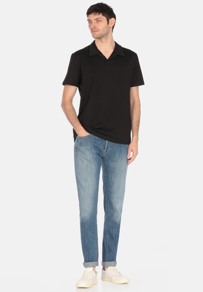 Polo shirt nero a maniche corte, jeans dritti blu chiaro e sneakers bianche. Design semplice con colletto e maniche arrotolate.