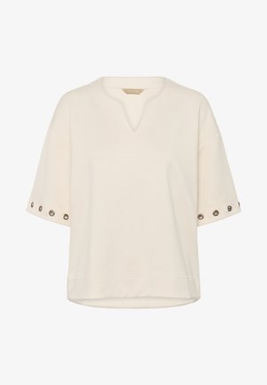 Kreemikat värvi lühikeste varrukatega top V-kaelusega, millel on varrukatel rauarõngaste aksessuaarid ja mugav lõige. Pehme kangatekstuur.