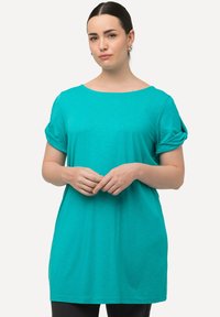 Tyrkysové oversized tričko s krátkými ohrnutými rukávy, vyrobené z měkké látky, s širokým výstřihem a volným střihem.