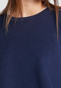 Camiseta azul marino de tela suave con cuello redondo, mangas cortas y un pequeño detalle bordado de "Hey Honey" en el pecho.