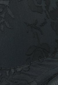 Svart tyg med ett texturerat blommönster, med släta och något upphöjda detaljer, samt en satinliknande finish längs kanterna.