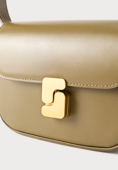 Λεπτή δερμάτινη τσάντα σε ελαιί πράσινο, με στρογγυλεμένες άκρες και χαρακτηριστικό χρυσό γεωμετρικό κούμπωμα στην εμπρόσθια πτέρυγα.