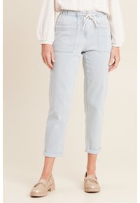 Lichtblauwe denim broek met een elastische tailleband, een trekkoordsluiting en twee voorzakken. Omgekrulde broekspijpen bij de enkel.