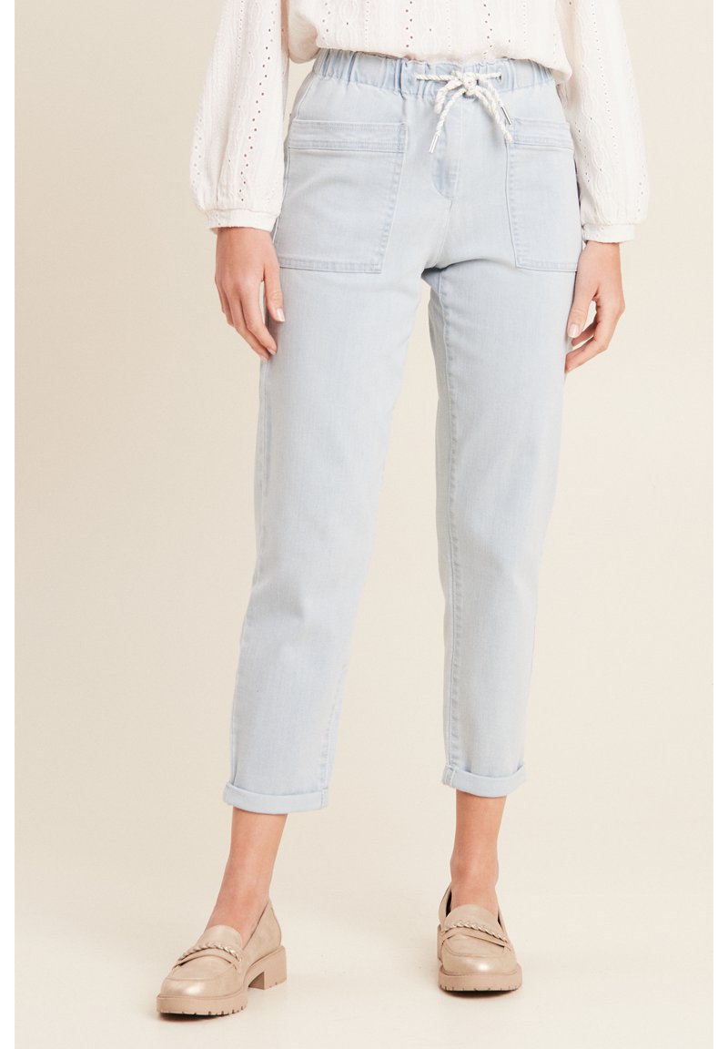 Lichtblauwe denim broek met een elastische tailleband, een trekkoordsluiting en twee voorzakken. Omgekrulde broekspijpen bij de enkel.