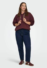 Bordo kapuce ar leopardu rakstu auklām, pārspīlēta piegriezuma, saskaņota ar tumši zilām džinsām un tumši sarkanām sporta apaviem ar baltu akcentu.