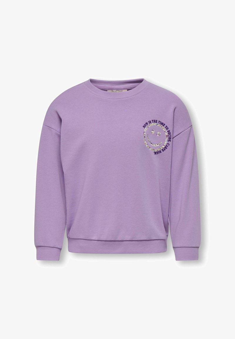 Sweatshirt lilas avec un col rond et des épaules tombantes. Présente un motif de visage souriant et le texte : "C'EST MAINTENANT QU'IL FAUT ÊTRE HEUREUX."