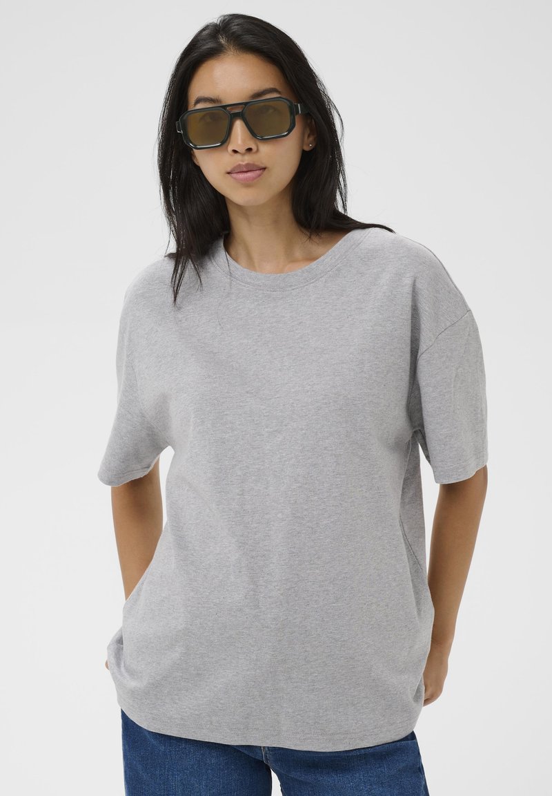 T-shirt gris en coton avec manches courtes et coupe décontractée. Le col rond présente une texture lisse et des poches latérales.