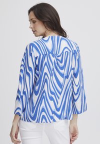 Cămașă cu mânecă lungă, cu un model abstract de valuri alb-albastre, realizată dintr-un material ușor, cu un decolteu rotund și un design cu spate despicat.
