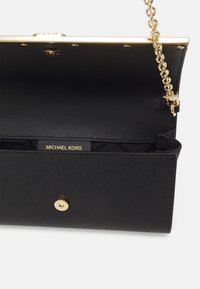 Mustmustnahk käekott tekstuurse viimistlusega, kuldne riistvara, klõpsuga sulgur ja ahel rihm. Märgistus kuldse "MICHAEL KORS" logoga.