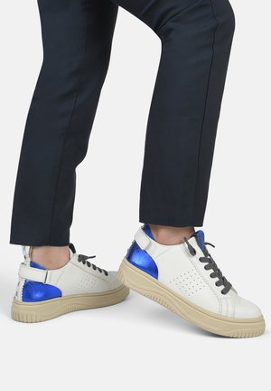 Sneakers bianchi in pelle con accenti metallici blu, lacci grigi e dettagli laterali perforati. Suola in gomma beige spessa per un maggiore comfort.