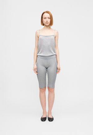 Graues, geripptes Tanktop mit verstellbaren Trägern, kombiniert mit passenden, knielangen, gerippten Shorts. Schwarze Ballerinas runden das Outfit ab.