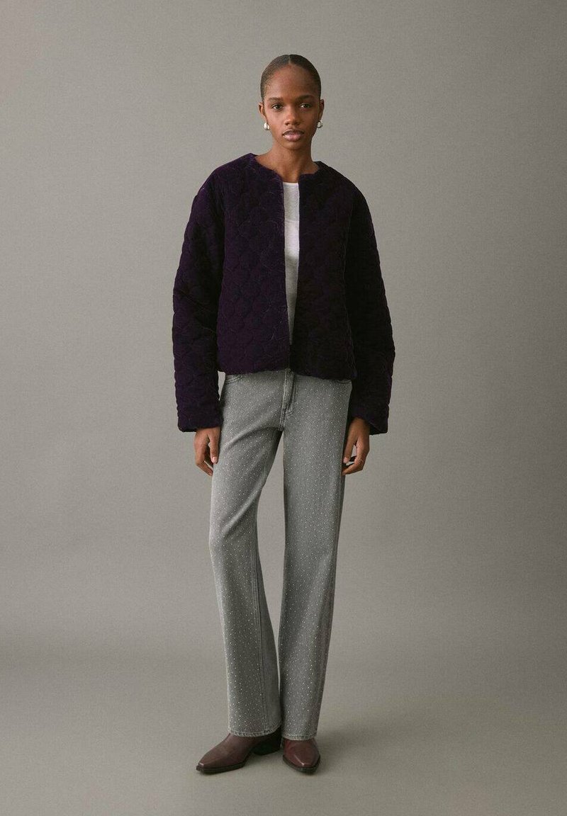 Giacca trapuntata viola con scollo rotondo, maniche lunghe e vestibilità corta; abbinata a pantaloni grigi chiari con una leggera scintilla.