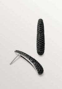 Pendientes de cristal negro con forma alargada y curva. Cuentan con un herraje en tono plateado brillante y una superficie lisa y texturizada.