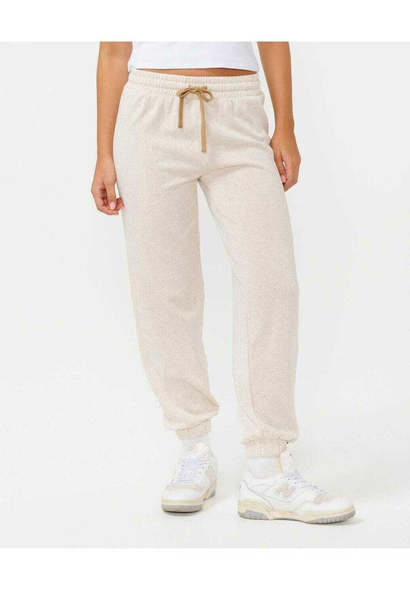 Ljusbeige joggerbyxor med dragsko i midjan, elastiska muddar och en mjuk textur, kombinerat med vita sneakers.