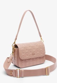 Sac à main synthétique rose matelassé avec un rabat plat, des ferrures dorées et une bandoulière en tissu réglable. Présente un motif géométrique sur la surface.