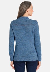 Maglione blu a maglia, collo rotondo, realizzato in filato testurizzato con un motivo a macchie. Presenta maniche lunghe e una silhouette leggermente aderente.