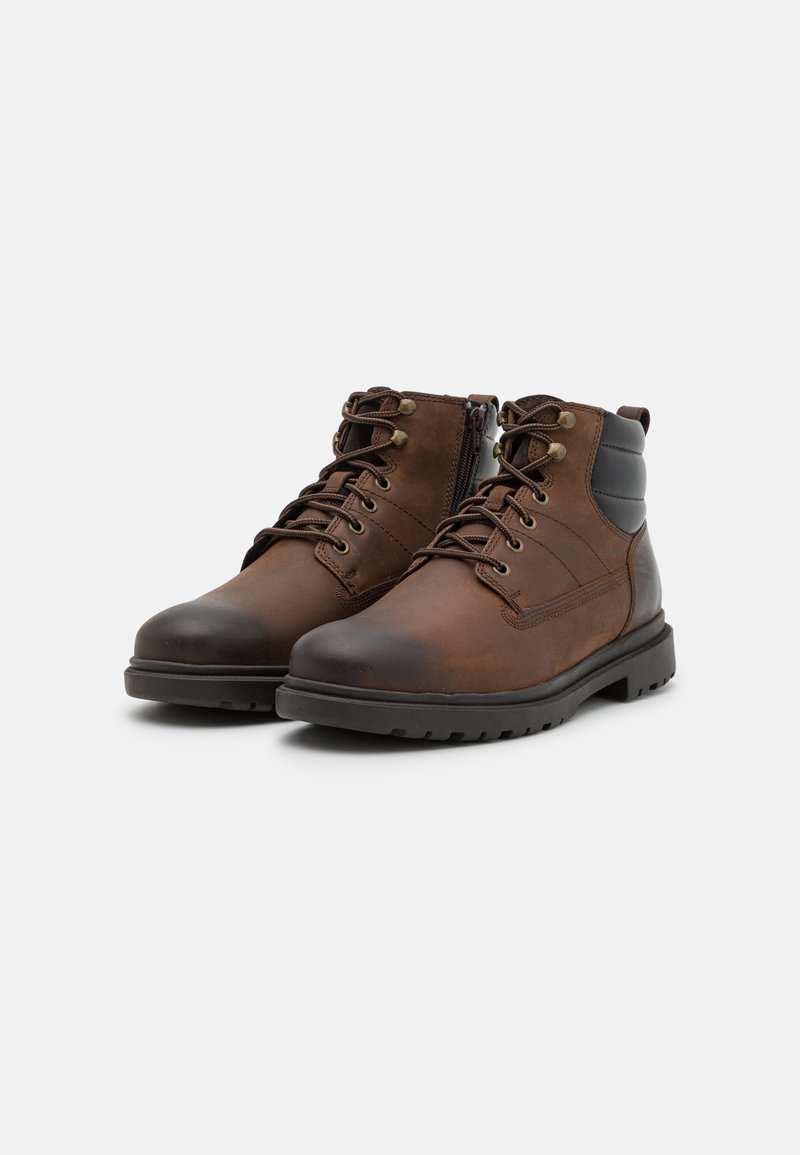 Bordeaux leren enkelboots met een gestructureerde afwerking, vetersluiting, stevige rubberen zool en subtiele contrasterende zwarte accenten bij de kraag.