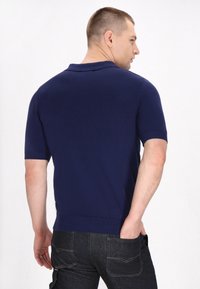 Námornícky polo shirt s krátkymi rukávmi z hladkej pleteniny, navrhnutý s priliehavým strihom a rebrovanými manžetami.