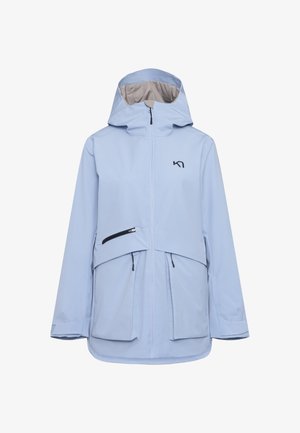 Giacca impermeabile azzurro chiaro con cappuccio, zip frontale, due grandi tasche e un logo nero discreto sul petto. Texture e design morbidi.