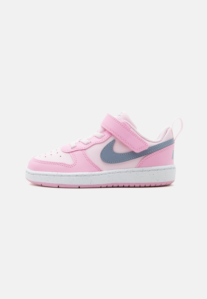 Παιδικό ροζ και λευκό αθλητικό παπούτσι Nike με γκρι λογότυπο swoosh, λουράκι βέλκρο, κορδόνια και λευκή σόλα με βούλες, σε πλάγια όψη.