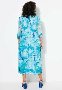 Lång blå blommig klänning med trekvartsärmar, med ett livligt tryck av stora blommor, lättviktig tyg och en flödande siluett.