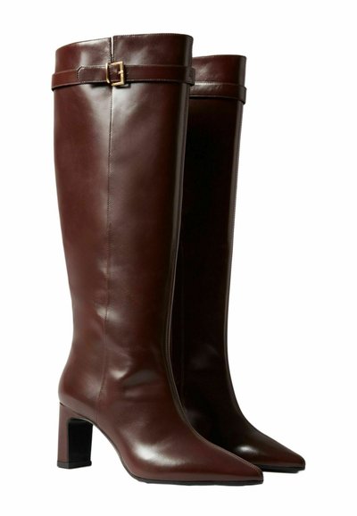 Botas de cuero marrón hasta la rodilla con tacón cuadrado, punta afilada y una correa decorativa con hebilla cerca de la parte superior. Textura suave y diseño elegante.
