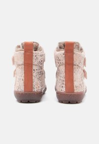Bottines rose clair avec motif floral et accents en cuir marron. Intérieur doux et texturé, avec deux sangles ajustables pour un bon maintien.