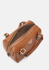 Brązowa torba skórzana o teksturze z złotymi zamkami błyskawicznymi, uchwytami z złotymi pierścieniami i beżowym wnętrzem z logo "Guess".