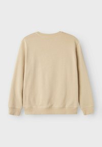 Sudadera beige de cuello redondo con mangas largas, puños y dobladillo de canalé, textura suave y un diseño simple, sin adornos.