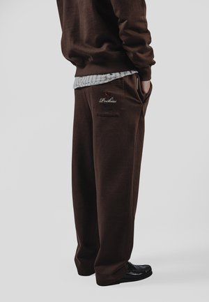 Brune joggebukser laget av mykt stoff, med en baklomme som har rød brodert "Pockies"-logo og sidelommer.