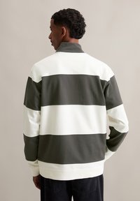 Green and white striped pullover sweatshirt, featuring a high collar and ribbed cuffs. The fabric appears soft, with contrasting dark accents.