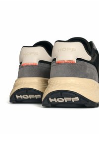 Zapatillas de ante gris con acentos beige, que cuentan con suelas de goma texturizadas y un atrevido logo "HOFF". Detalle de costura naranja en el talón.
