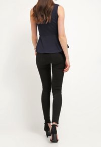 Námořnický peplum top bez rukávů, kombinovaný s černými přiléhavými legínami a lodičkami na kotníkovém pásku. Hladká textura po celém povrchu.
