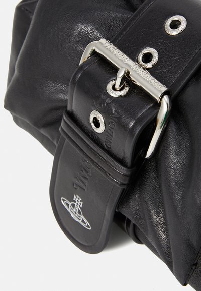 Melna ādas somiņa ar faktūru, ar sudraba detaļām, ar logotipu iegravētu siksnu un acīm, kas piešķir papildu detaļas.