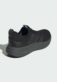 Čierna atletická obuv s pleteným vrchom a koženými doplnkami. Obsahuje hrubú podrážku, pútko a trojpruhový dizajn na boku.