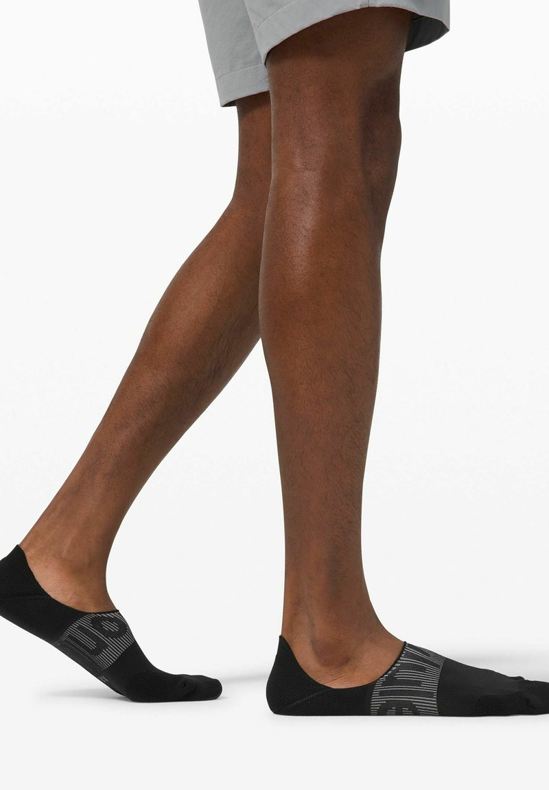 Mustat matalat sukat, joissa on teksturoidut mustat ja harmaat raidat sekä kuvioitu palkki. Valmistettu sileästä, joustavasta materiaalista mukavuutta varten.