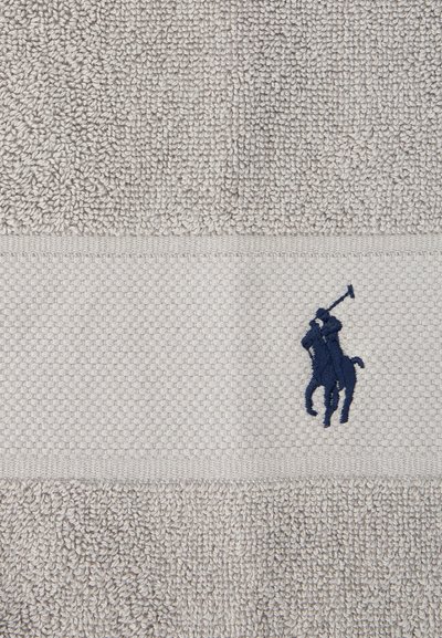 Μπεζ πετσέτα με υφή και υφασμάτινη ταινία που απεικονίζει έναν ναυτικό μπλε κεντημένο αναβάτη πόλο που κουνά ένα σκαλιστήρι.