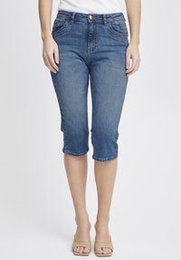 Denim capri hlače v srednjem modrem odtenku. Imajo pet žepov, šivano podrobno obdelavo in zavihane robove na sredini teleta. Narejene so iz mehkega, raztegljivega bombažnega blaga.