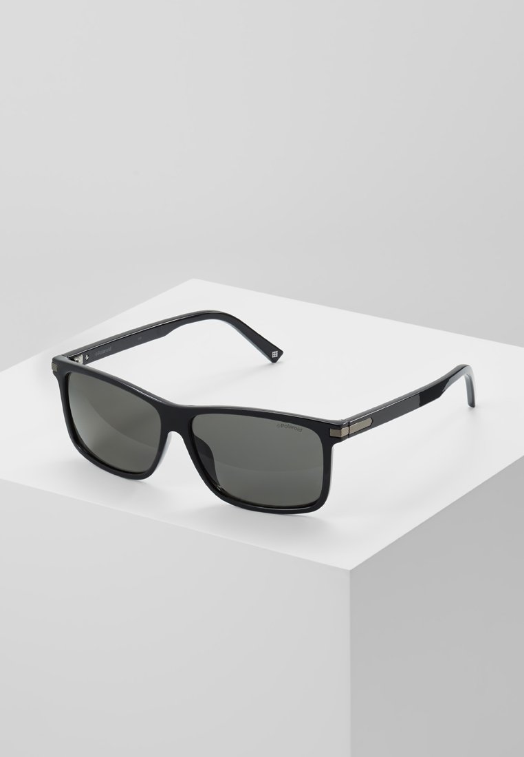 Ochelari de soare dreptunghiulari negri cu lentile gri, ramă din plastic lucios și accente metalice pe tempură. Design minimalist.
