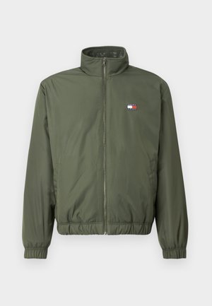 Giacca puffer verde oliva con colletto alto, zip frontale, polsini e orlo elasticizzati, caratterizzata da un piccolo logo ricamato sul petto.