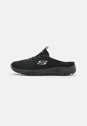 Czarny sneaker wsuwany z siateczkową tkaniną, ozdobami z sznurowadeł, elastyczną podeszwą i srebrnym logo "S" z boku, widoczny od zewnętrznej strony.