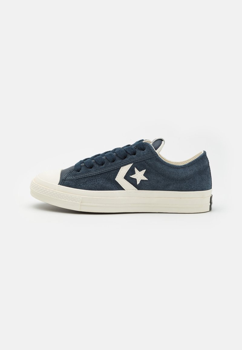 Baskets basses en daim bleu marine avec semelle en caoutchouc blanche, logo étoile blanche et chevron sur le côté, lacets bleu marine, vues de côté gauche.