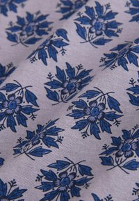 Textil med en ljus lavendelfärgad bakgrund som har ett upprepande mönster av blå blommor och blad, vilket ger intrikata detaljer och textur.