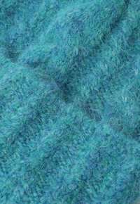 Tessuto strutturato in diverse sfumature di teal e blu, con una superficie morbida e pelosa, realizzata con un mix di fibre che creano profondità e movimento.